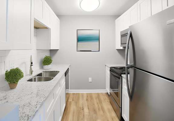 a modern kitchen with stainless steel appliances and white cabinets at Creekside Canopy, Charlotte North Carolina
