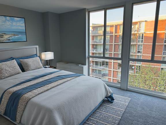 A bedroom with a bed, chair, and lamp.
