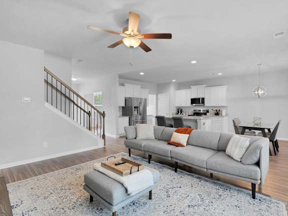 A modern living room with a grey sofa and a ceiling fan.