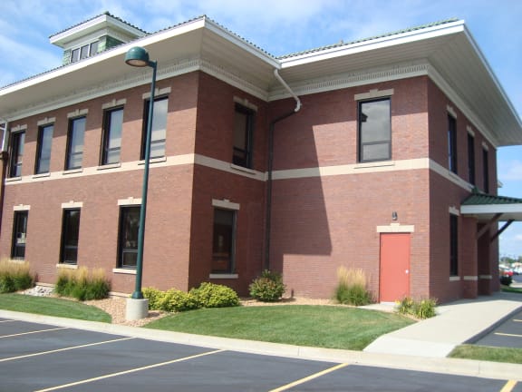 a brick building with a red door and a lawn