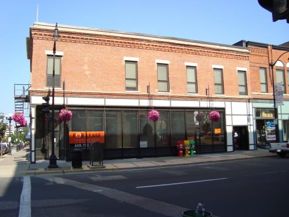 the front of a brick building with flowers on the street