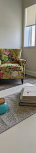 A living room with a floral print chair and a coffee table and a television