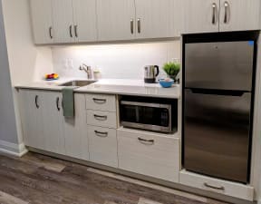 A kitchen with white cabinets and a stainless steel refrigerator
