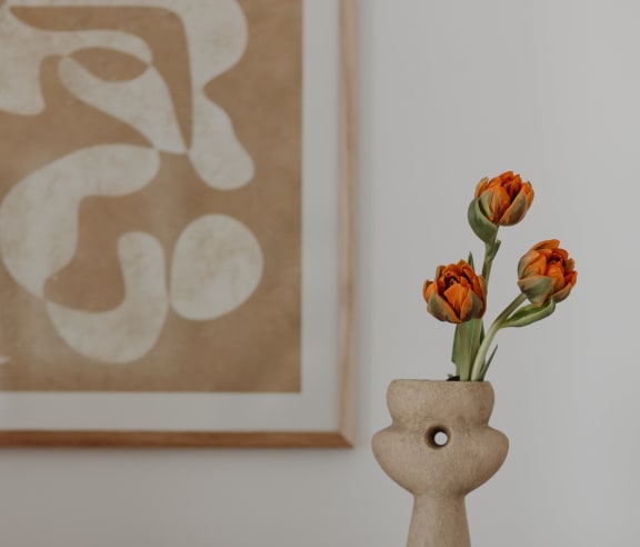 a vase with orange tulips on a table with books and a pair of glasses