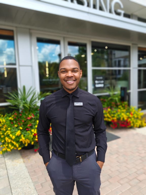 a man in a black shirt and tie standing in front of a building