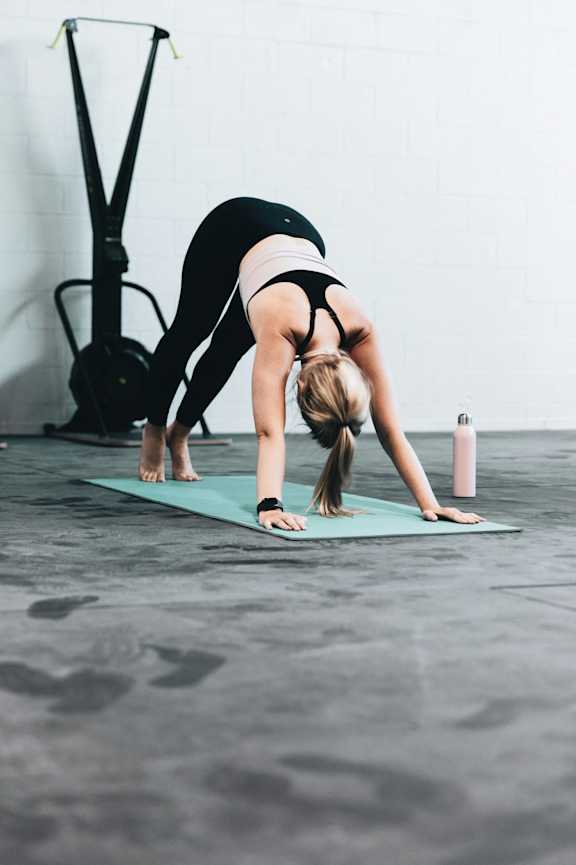 A woman is doing a yoga pose on a green mat.