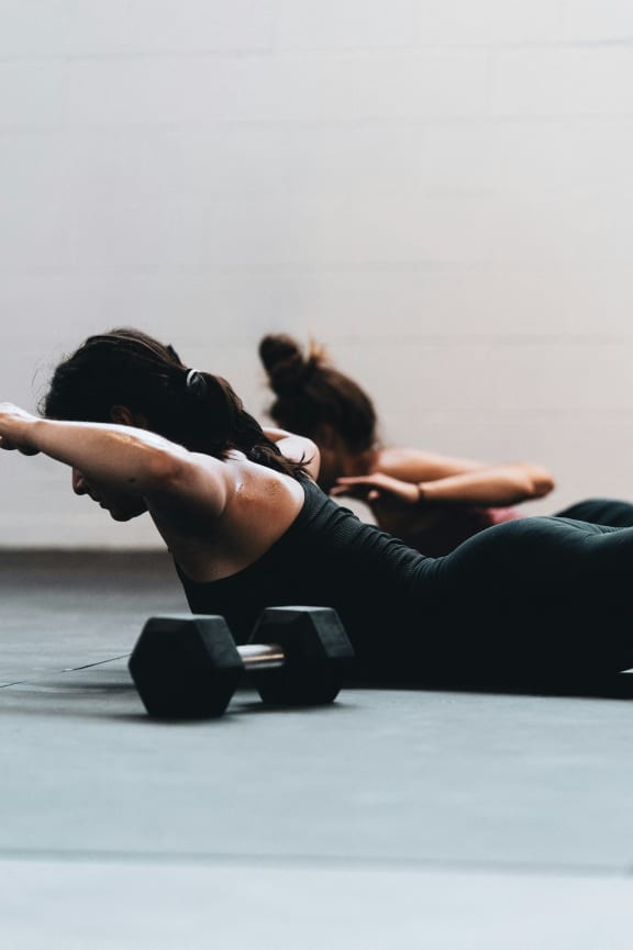 two women in a yoga class with dumbbells