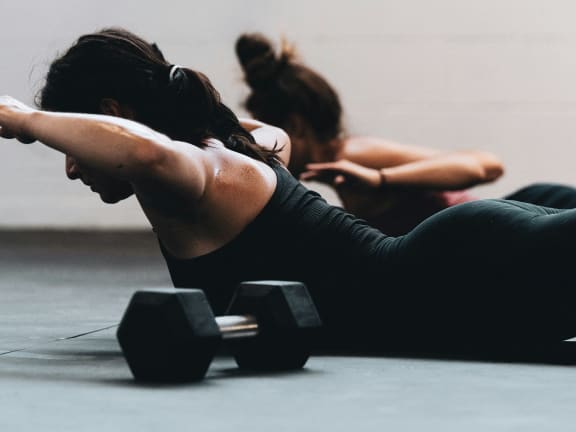 two women in a yoga class with dumbbells