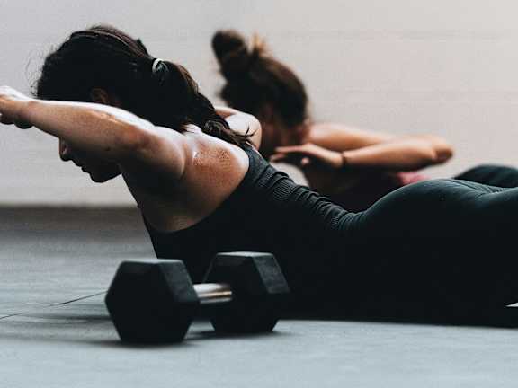 A woman is doing a workout with dumbbells in a gym.