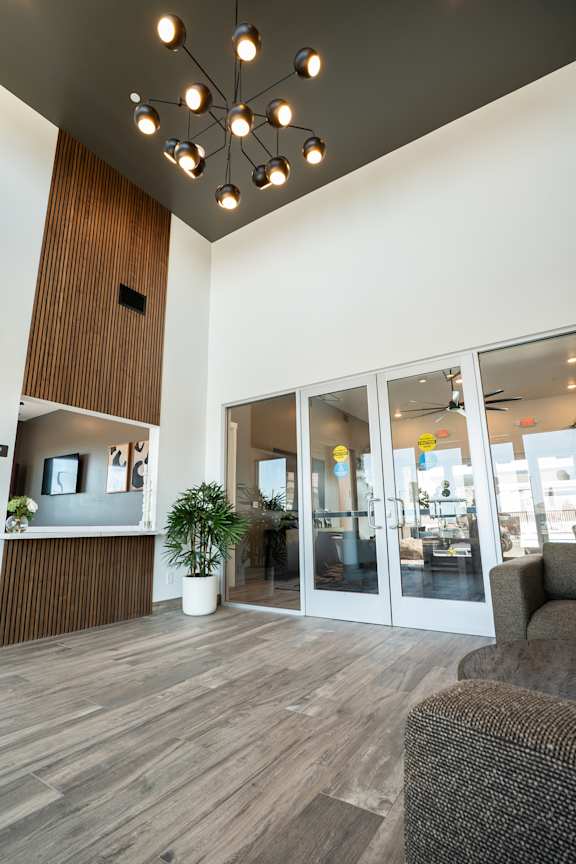 A modern office lobby with a wooden panel on the wall and a ceiling light fixture.