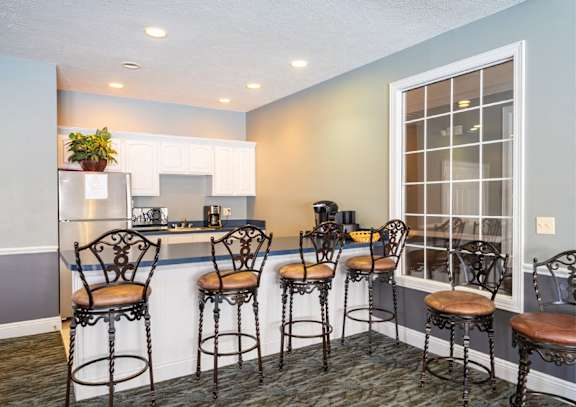 a bar area with bar stools and a kitchen with a window