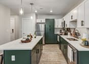Thumbnail 1 of 33 - a kitchen with green cabinets and white counters and a stainless steel refrigerator at Edgebrook Residences, Merrimack, NH 03054