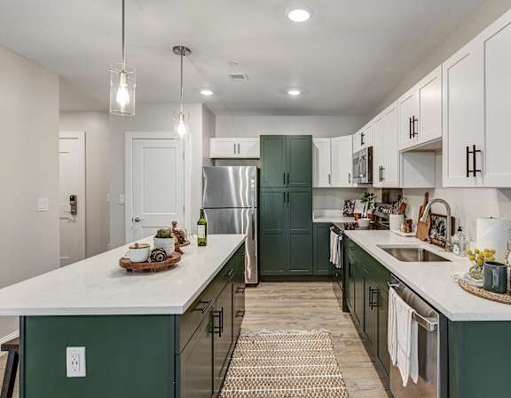 a kitchen with green cabinets and white counters and a stainless steel refrigerator at Edgebrook Residences, Merrimack, NH 03054