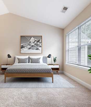 A bedroom with a bed, desk, chair, and a painting on the wall.