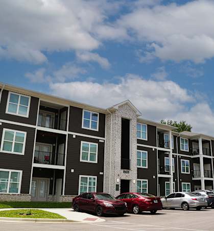 A large apartment building with a parking lot in front.