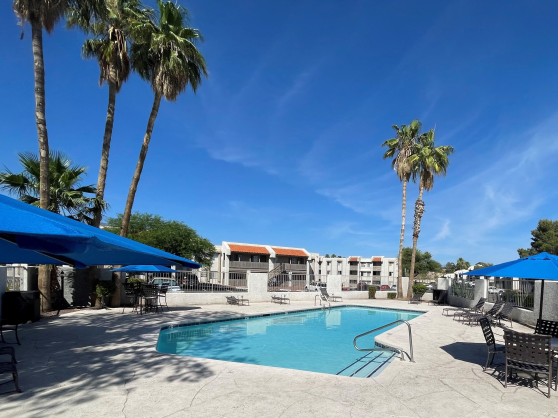 a swimming pool at a hotel with tables and chairs around it