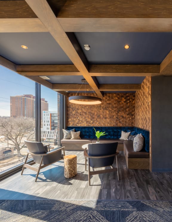 a living room with a blue couch and two chairs and a large window with a city view