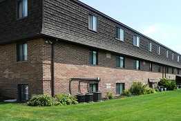 A long brick building with a green lawn in front.