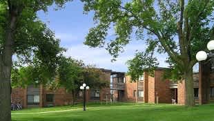 A green lawn in front of a brick building.
