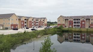 Apartment buildings are reflected in the water.