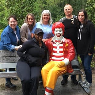 a group of people posing with a person dressed up as a clown on a bench