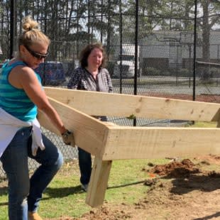 two women are building a wooden fence in a field