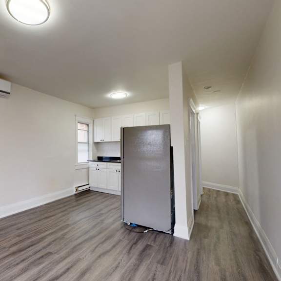 A kitchen with a table and chairs in the foreground and a refrigerator in the background.