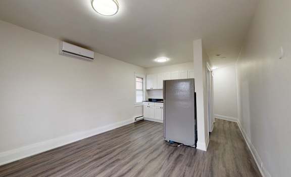 A kitchen area with a refrigerator and a television.
