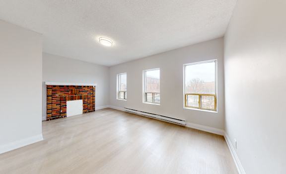 A room with a fireplace and three windows.