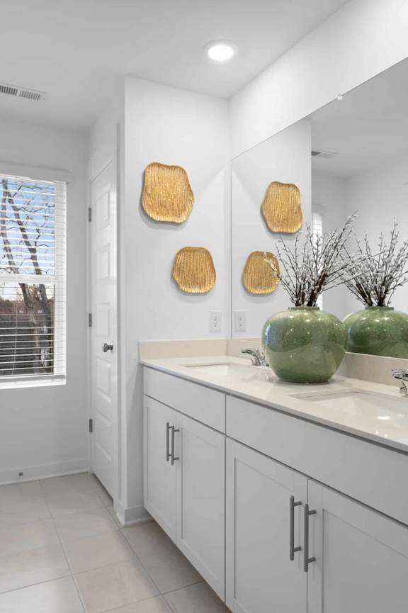A bathroom with white cabinets and a large mirror.