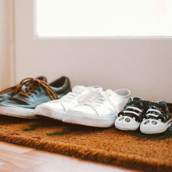 Pairs of shoes are on a rug in front of a door.
