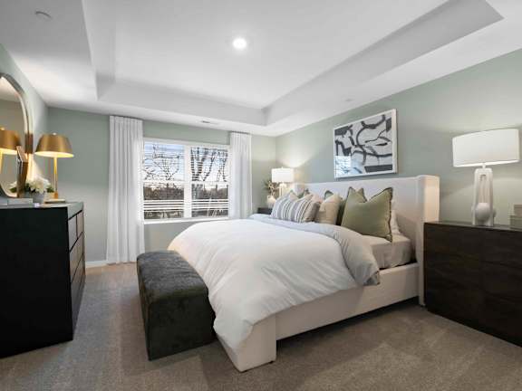 A bedroom with a large bed, a dresser, and a mirror.
