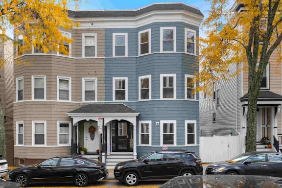 A row of houses with cars parked in front.