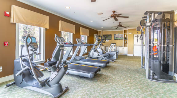 a room filled with cardio equipment and a ceiling fan