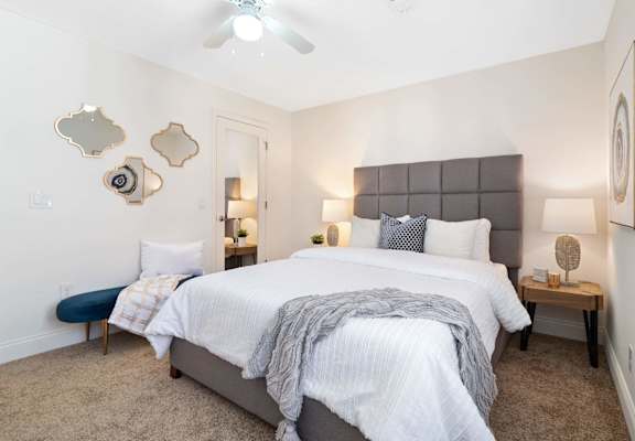 A bedroom with a large bed and a ceiling fan.