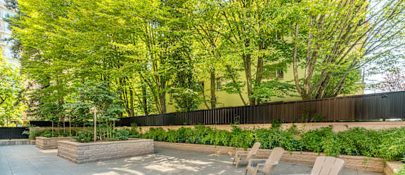 A patio with chairs and a table surrounded by a fence and trees.