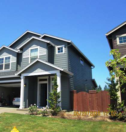 A grey house with a white truck parked in front.