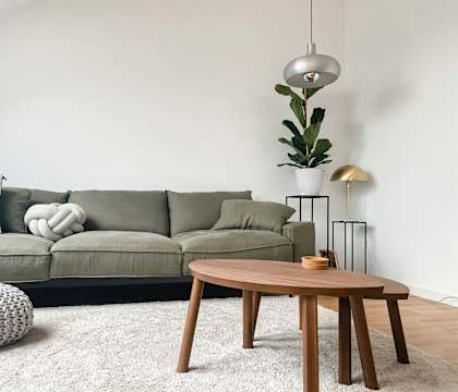 A living room with a grey couch, a wooden table, and a rug.
