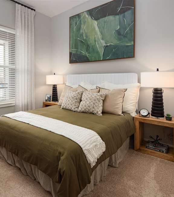 a bedroom with a bed and a large green painting