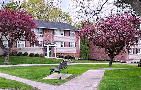 a bench sits in the middle of a grassy area in front of a brick building