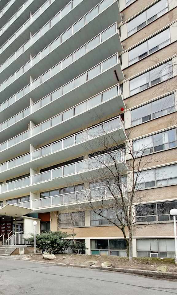 A tall residential building with a pool in front.