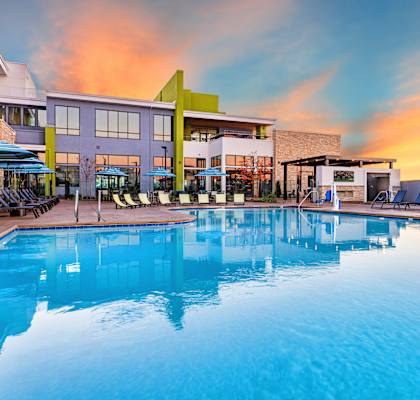 a swimming pool at a resort with a sunset in the background at Zeta Luxury Apartments in Sacramento, CA