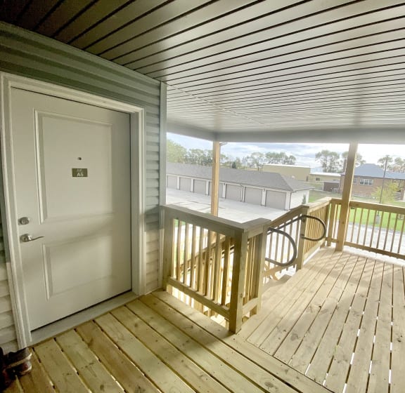 the deck of a home with a white door and a porch