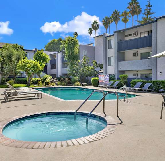 A swimming pool surrounded by a patio with chairs and umbrellas.