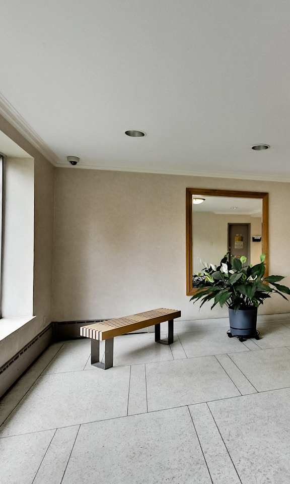 a hallway with benches and a potted plant and a large window