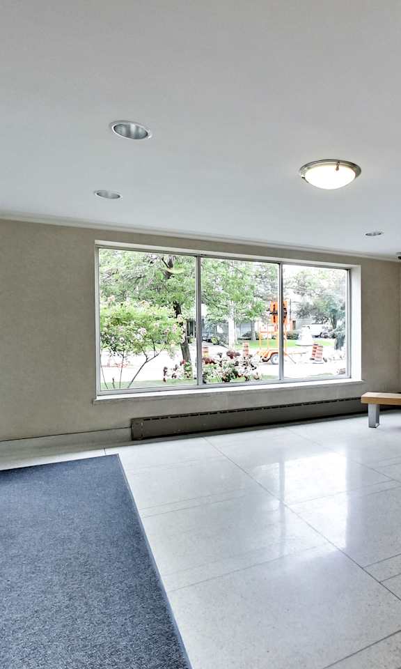 an empty living room with a large window and a potted plant