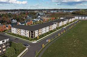 A large apartment complex with a parking lot in front.