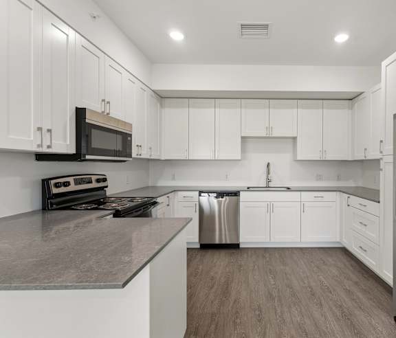A modern kitchen with white cabinets and stainless steel appliances.