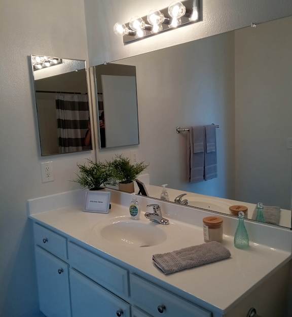 A bathroom with a sink, mirror, and lights.