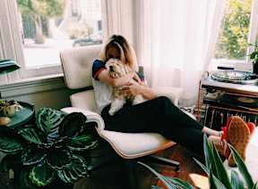 A woman is sitting on a chair holding a dog.